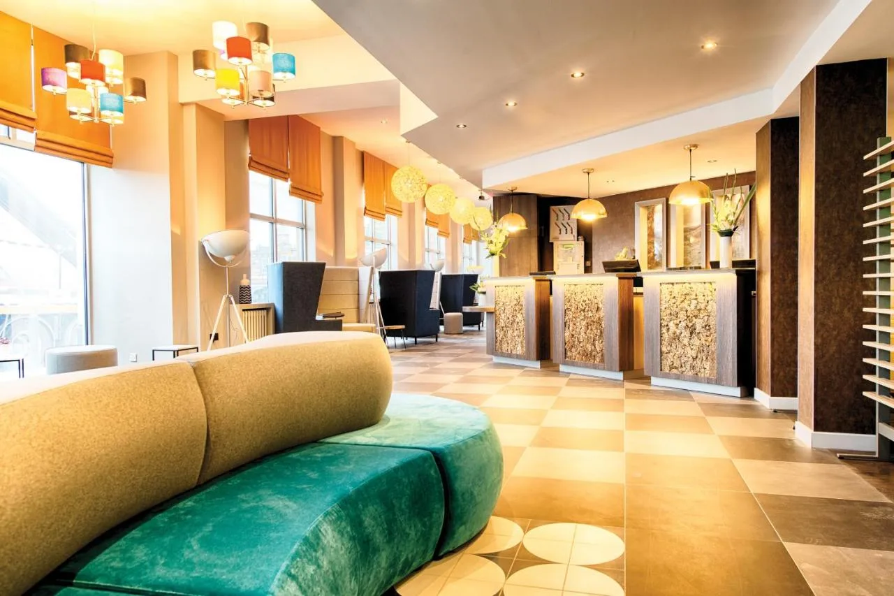 a salon with a couch in the middle of a room at Leonardo Hotel Edinburgh Haymarket in Edinburgh