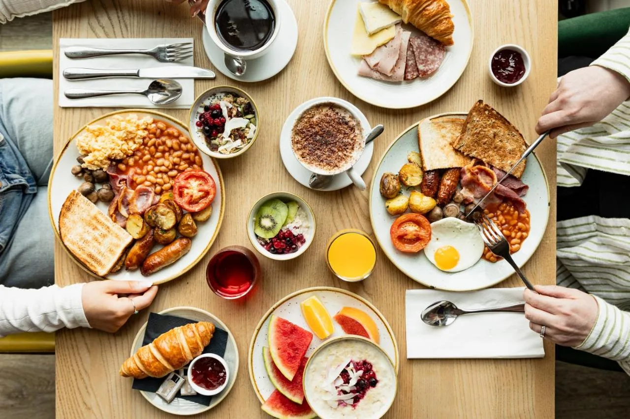 a table with plates of breakfast food on it at Leonardo Hotel Edinburgh Haymarket in Edinburgh
