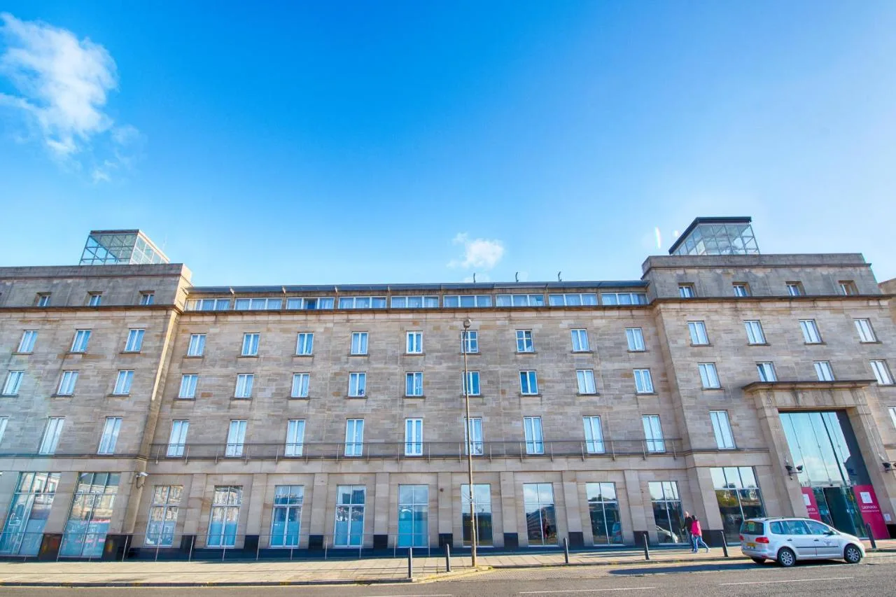 a large building with a car parked in front of it at Leonardo Hotel Edinburgh Haymarket in Edinburgh
