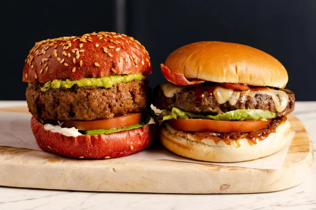 two hamburgers sitting on a wooden cutting board at Leonardo Hotel Edinburgh Haymarket in Edinburgh